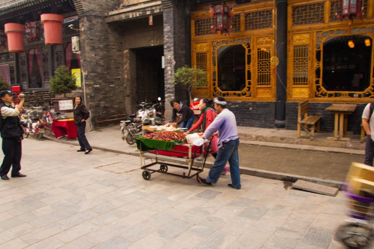 A vendor pushing a cart on a street in Pingyao.