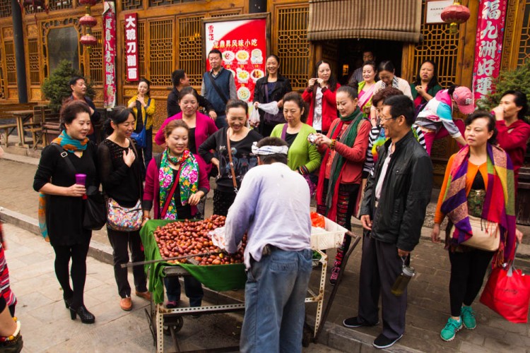 A street vendor offering dates from a cart to a group of women in Pingyao.