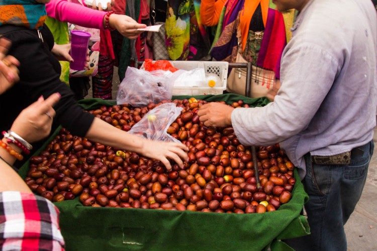 Hands picking up dates from a cart.
